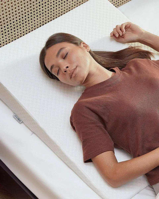 Woman sleeping on a white wedge pillow for acid reflux, designed for comfort and support