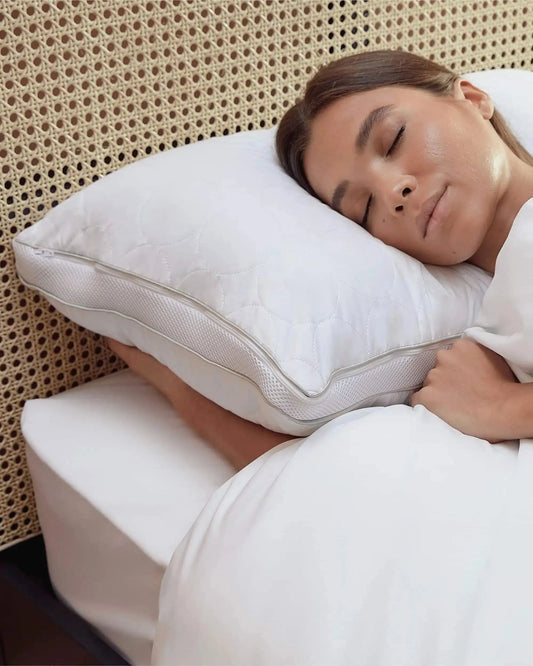 Woman sleeping on an adjustable ergonomic white pillow in a cozy bedroom setting