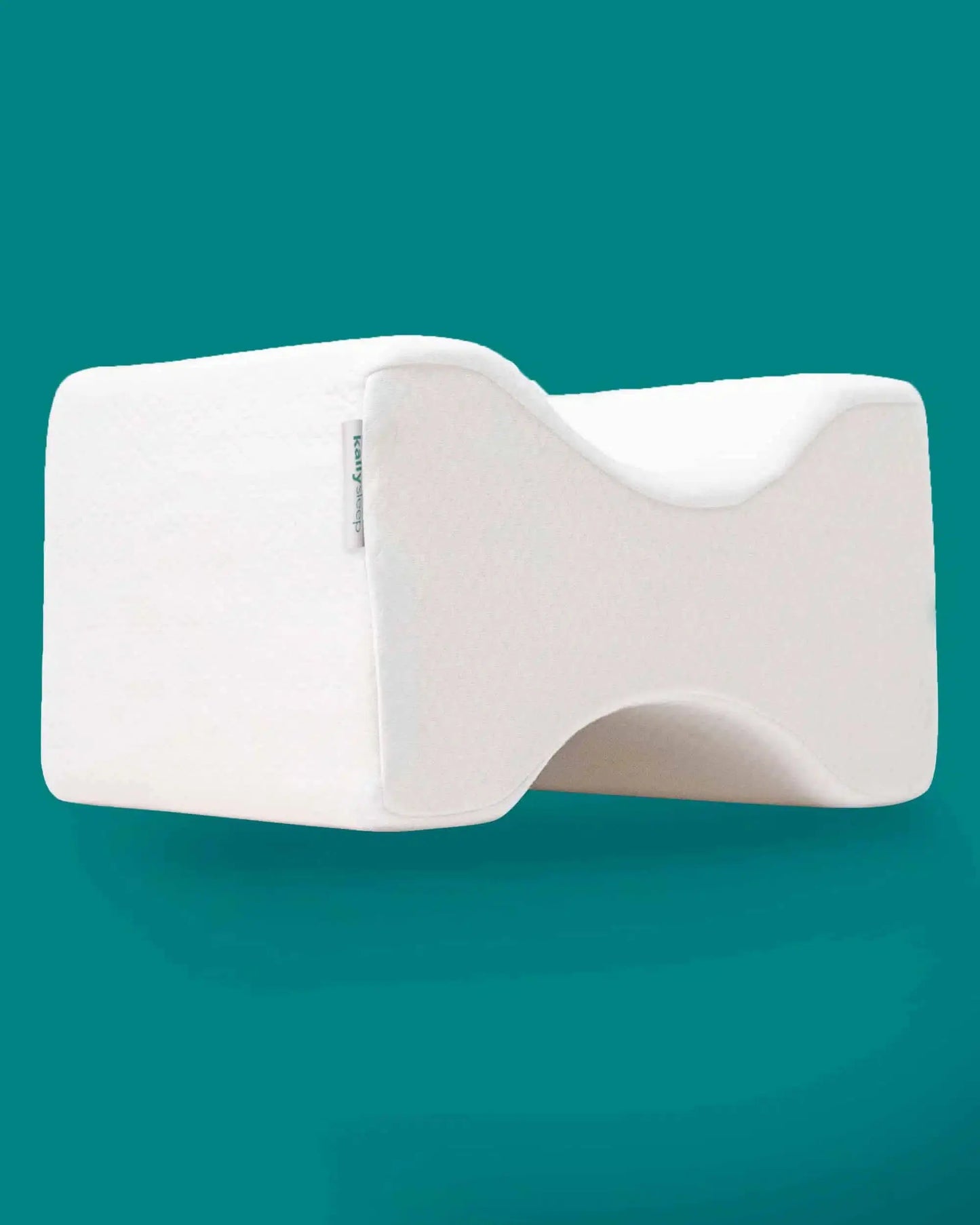 Ergonomic memory foam knee pillow for posture support against teal background