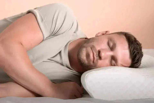 Woman massaging neck in bed with pained expression illustrating neck pain at night and sleep discomfort