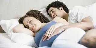 Pregnant woman sleeping comfortably with maternity pillow for good night's sleep during pregnancy